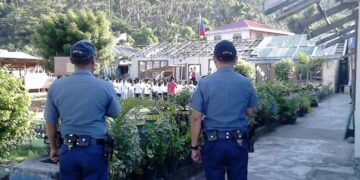 Two police personnel pays respect to the PH flag during the opening of class in Concepcion town. (Photo: Concepcion MPS)